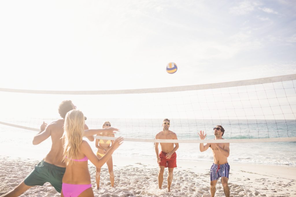 Happy friends playing beach volleyball on the beach